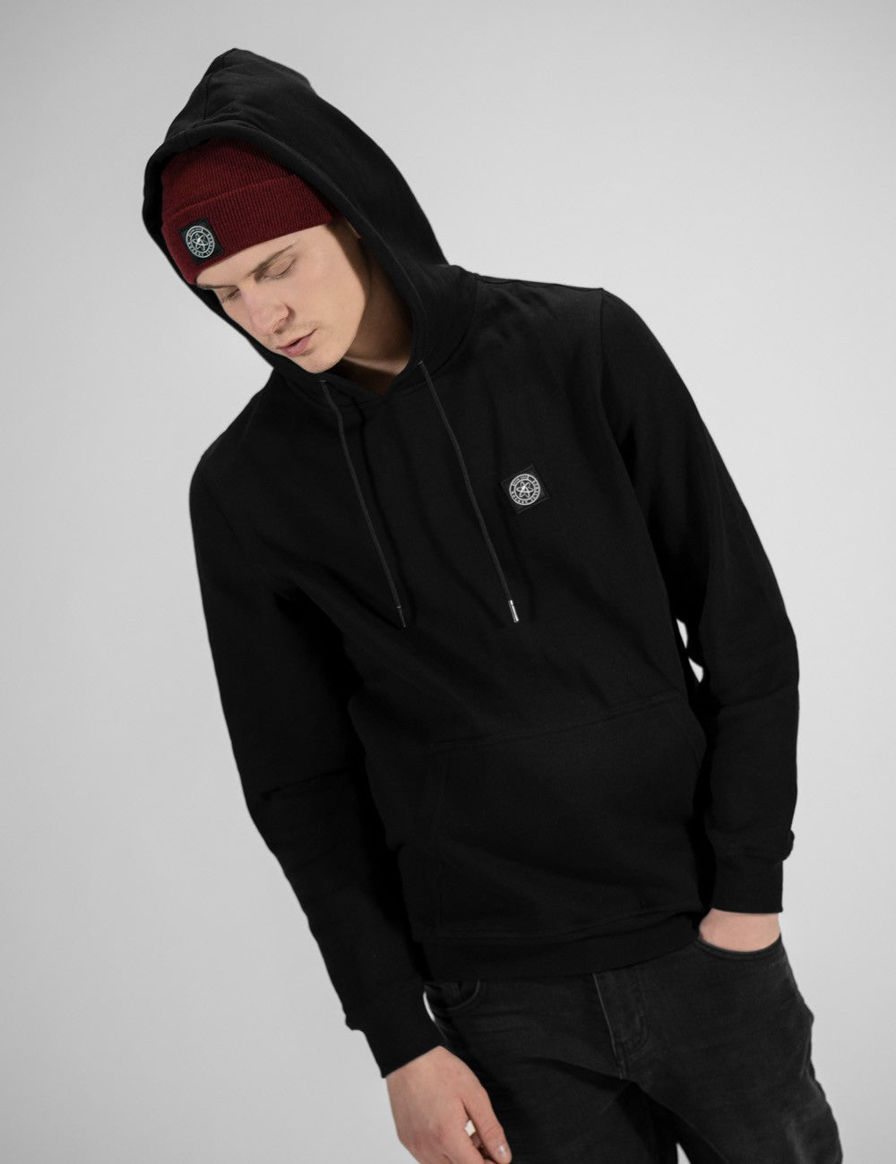 Man showcasing a burgundy heavy-knit beanie with a Rocket Science logo on the front.