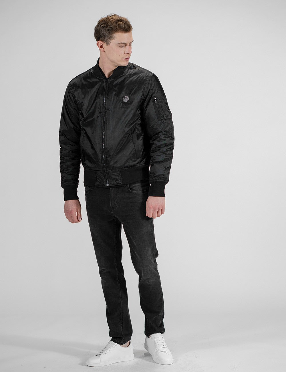 The model in the image is wearing a black Rocket Science Bomber Jacket featuring a stand-up collar, zip closure, and a chest patch label.