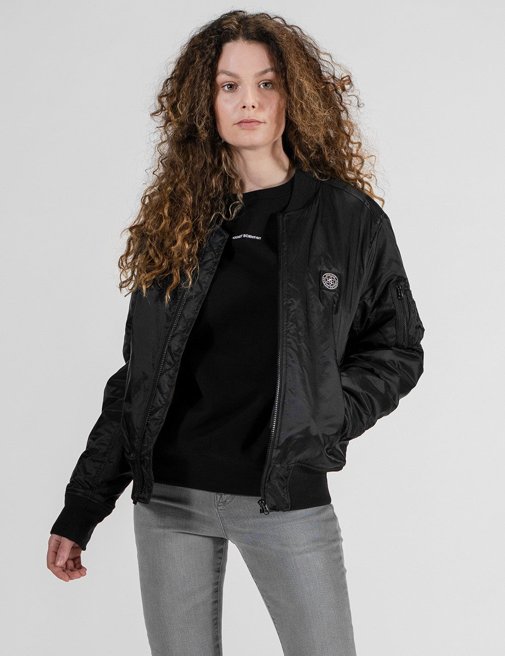 The model is wearing a black Rocket Science Bomber Jacket