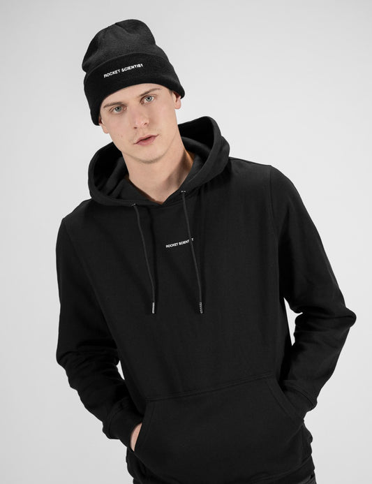 Man showcasing a black heavy-knit beanie with a Rocket Science logo on the front
