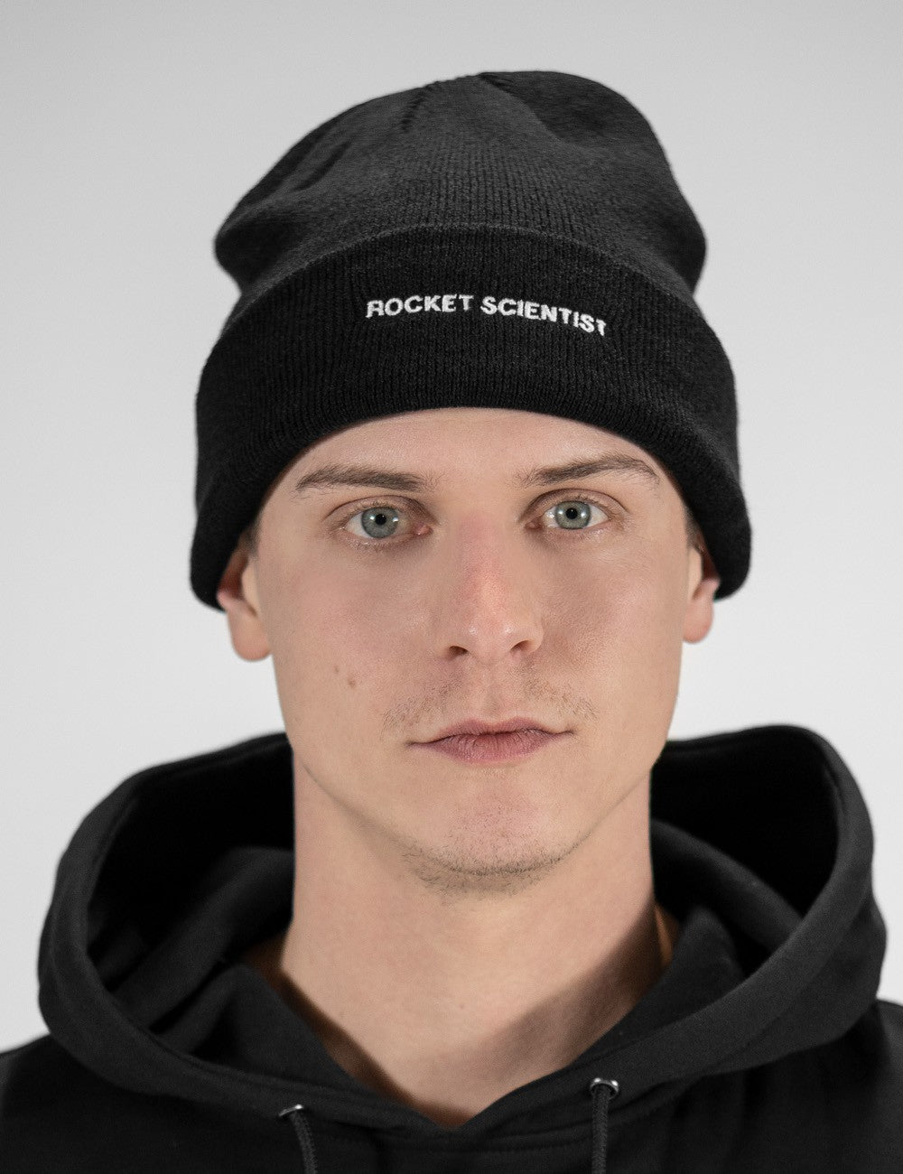 Man showcasing a black heavy-knit beanie with a Rocket Science logo on the front
