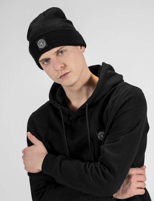 Man showcasing a black heavy-knit beanie with a Rocket Science logo on the front
