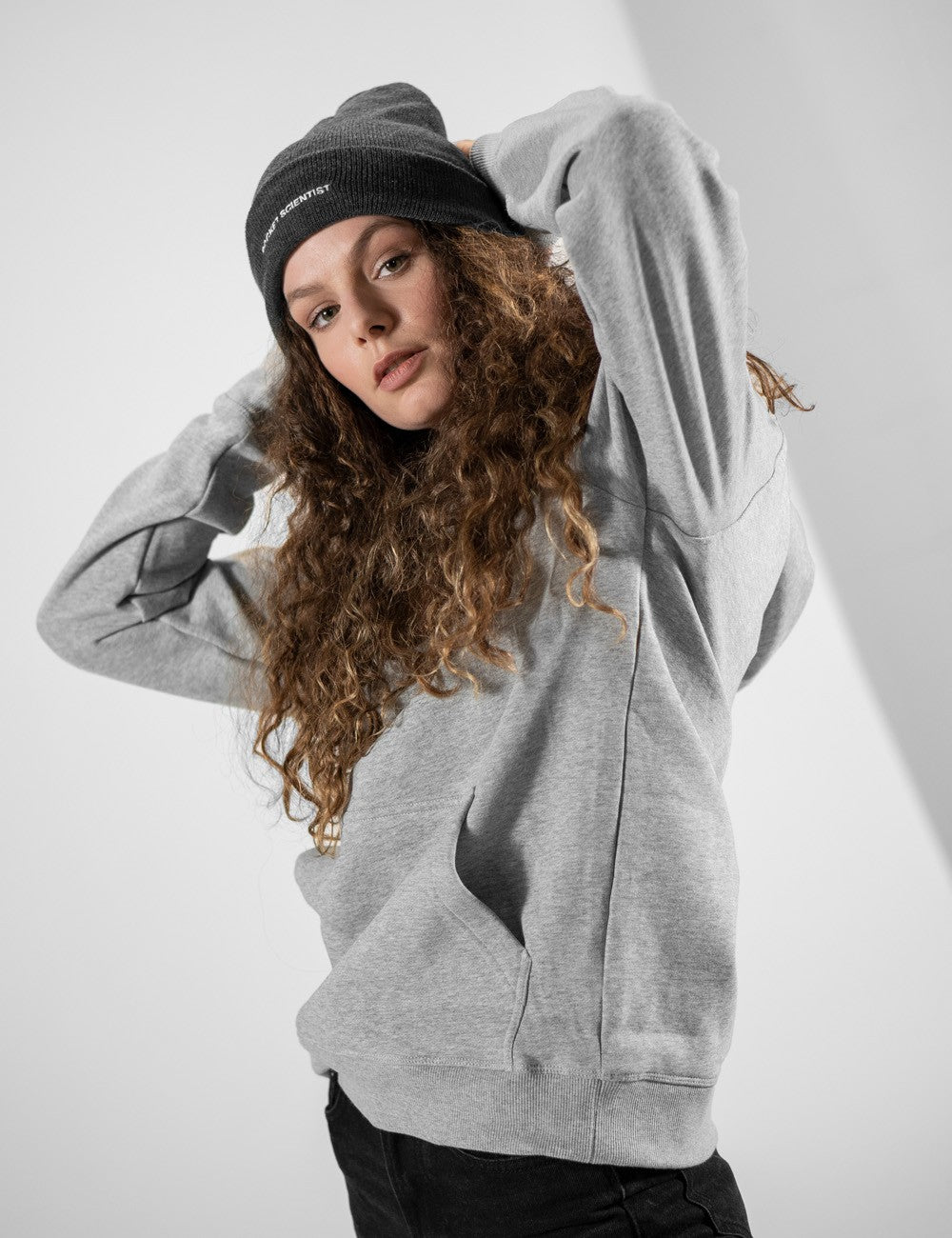 Woman showcasing a charcoal heavy-knit beanie with a Rocket Science logo on the front.