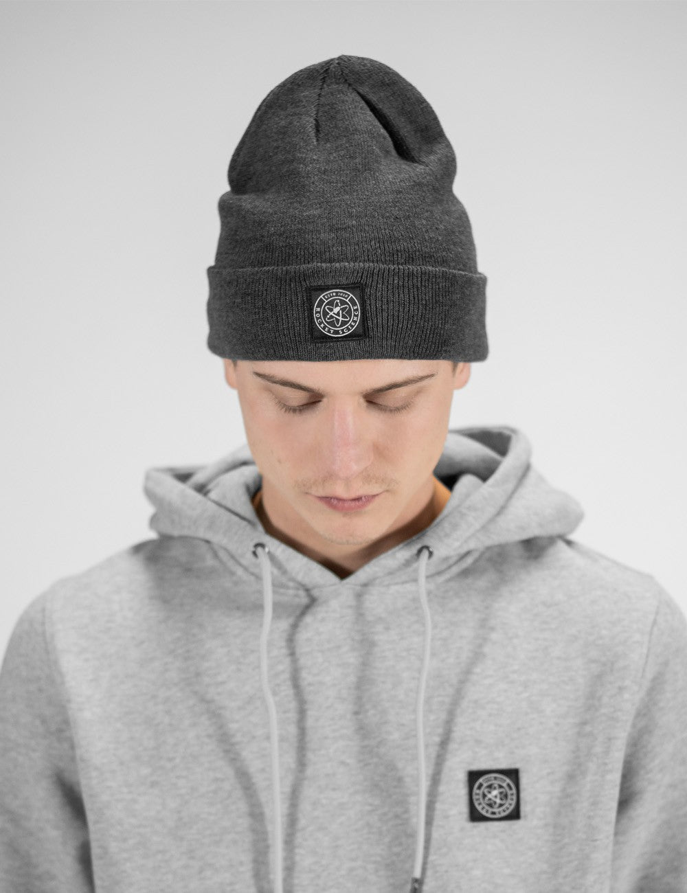 Man showcasing a charcoal heavy-knit beanie with a Rocket Science logo on the front.