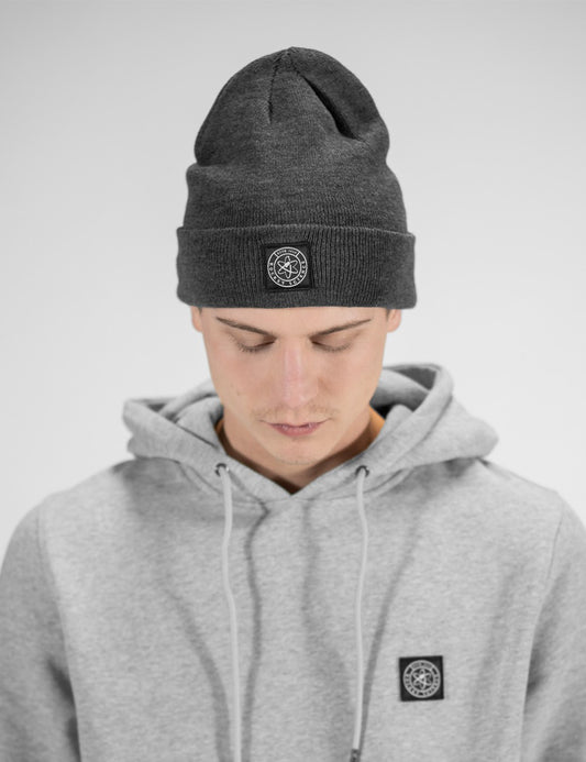Man showcasing a charcoal heavy-knit beanie with a Rocket Science logo on the front.
