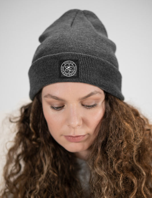 Woman showcasing a charcoal heavy-knit beanie with a Rocket Science logo on the front.