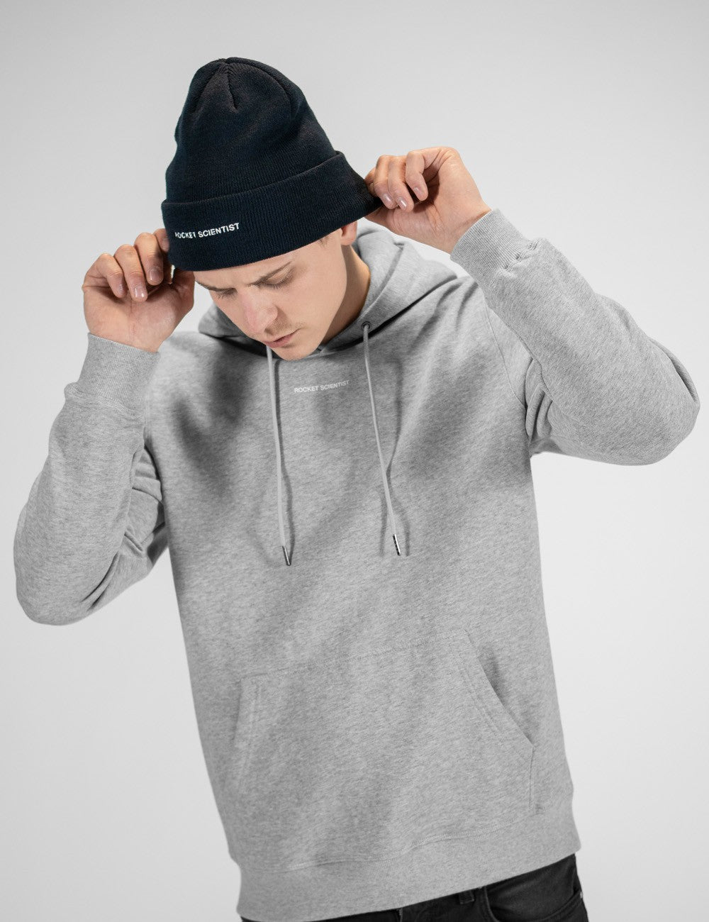 Man showcasing a navy heavy-knit beanie with the words “Rocket Scientist” on the front.