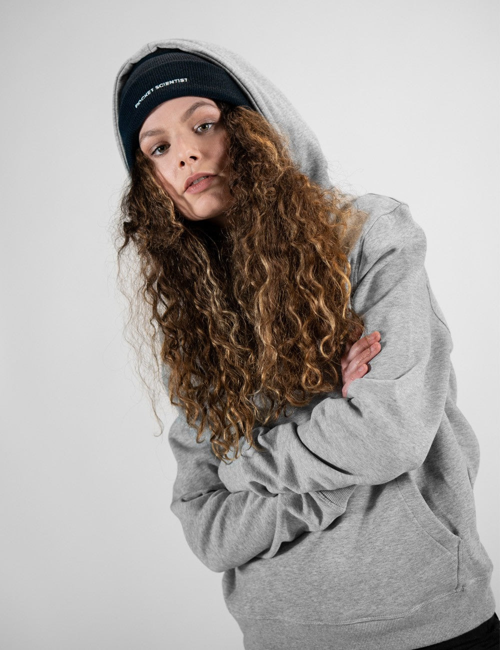 Woman showcasing a navy heavy-knit beanie with the words “Rocket Scientist” on the front.