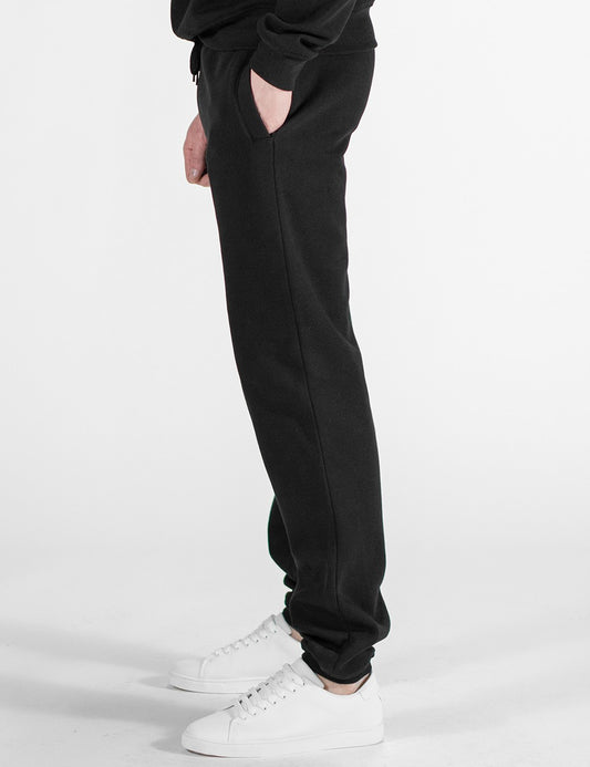 This image shows a side pose of person wearing black sweatpants, paired with white sneakers.