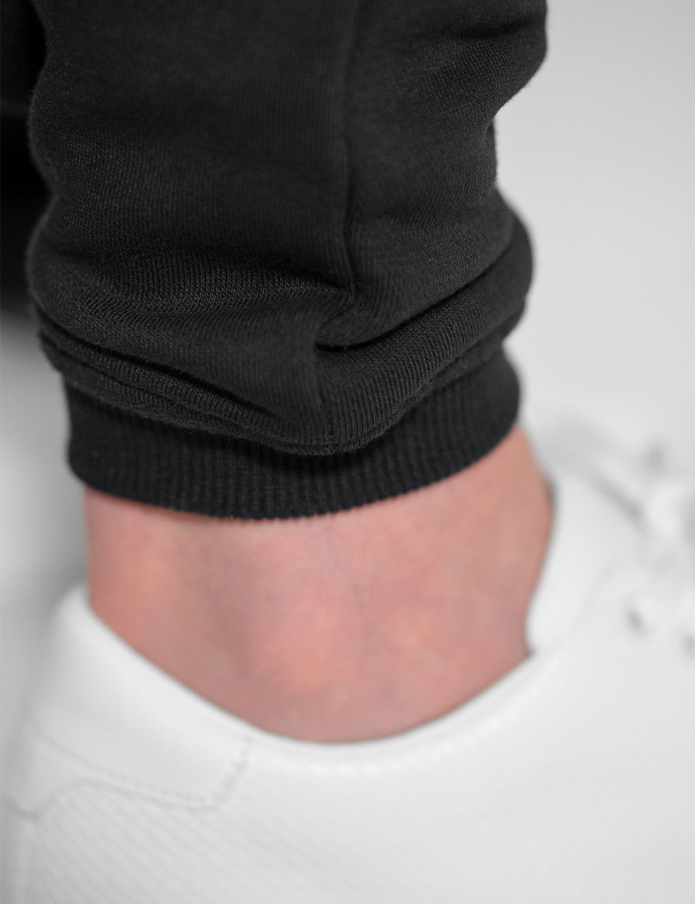 The image shows a pair of black jogger sweatpants from Rocket Science with ribbed ankle cuffs paired with white sneakers.