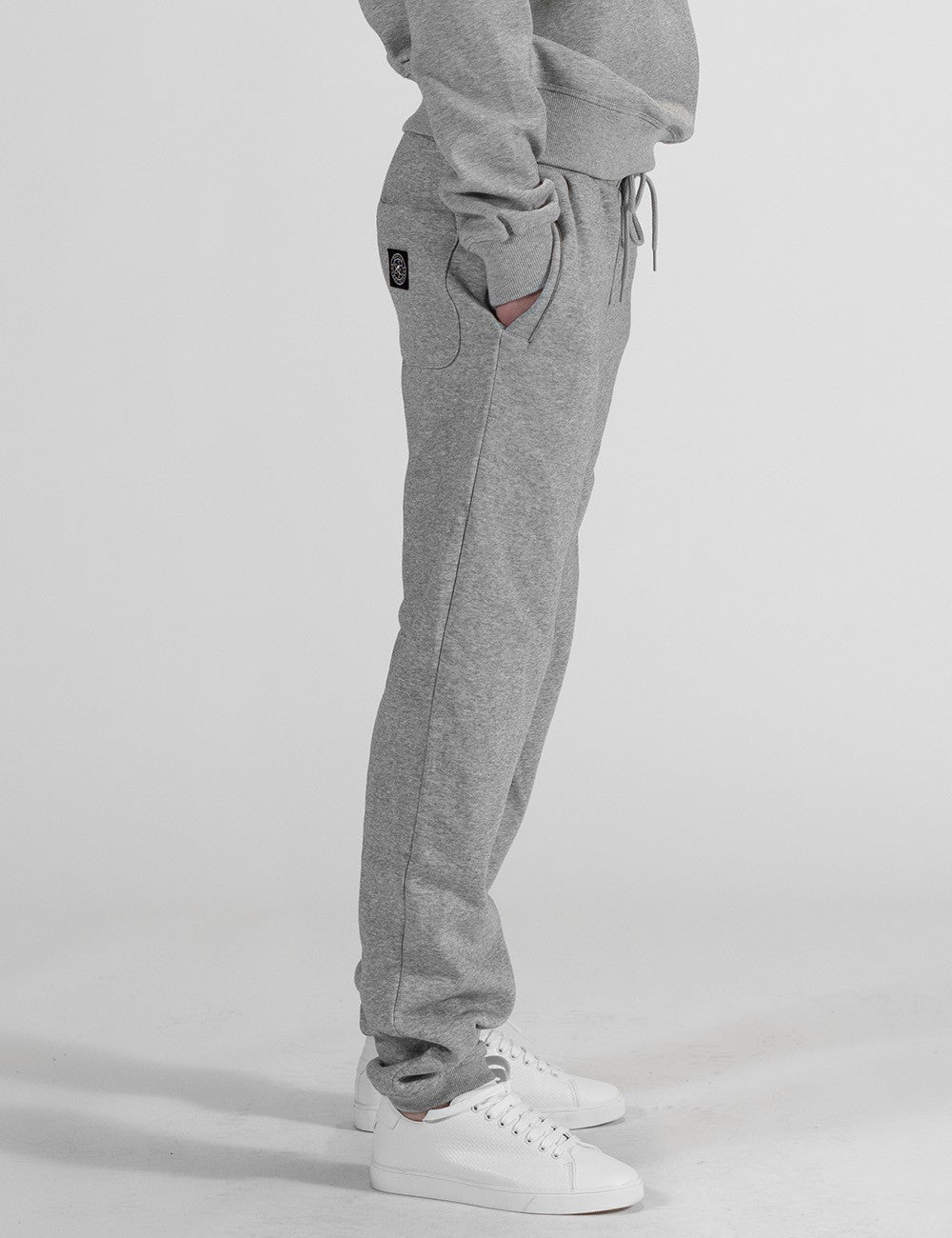 The image shows a pair of grey heather sweatpants with an elastic waistband, drawstrings, and a small square Rocket Science logo patch on the back pocket area.