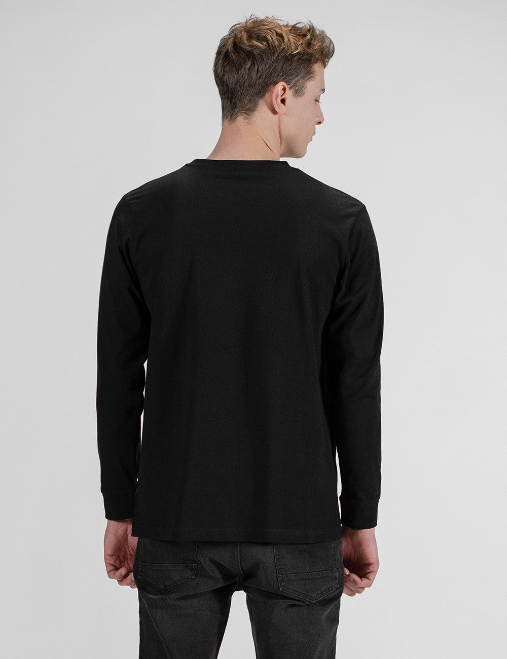 This image shows a rear pose of a young man wearing a plain black long-sleeve crewneck shirt .
