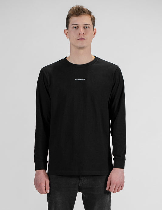 This image shows a young man wearing a plain black long-sleeve crewneck t-shirt with a small Rocket Scientist logo print on the chest.