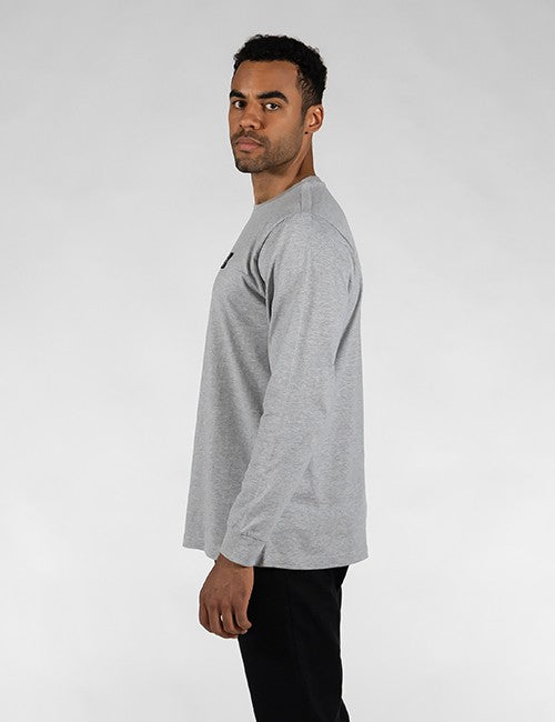 A man wearing a light gray long-sleeve crewneck t-shirt, shown from a side profile against a light gray studio background.
