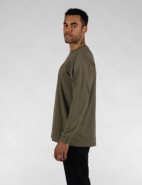 An olive green long-sleeve t-shirt is worn by a man with short dark hair and a light beard, shown in a side profile against a plain, light grey background.