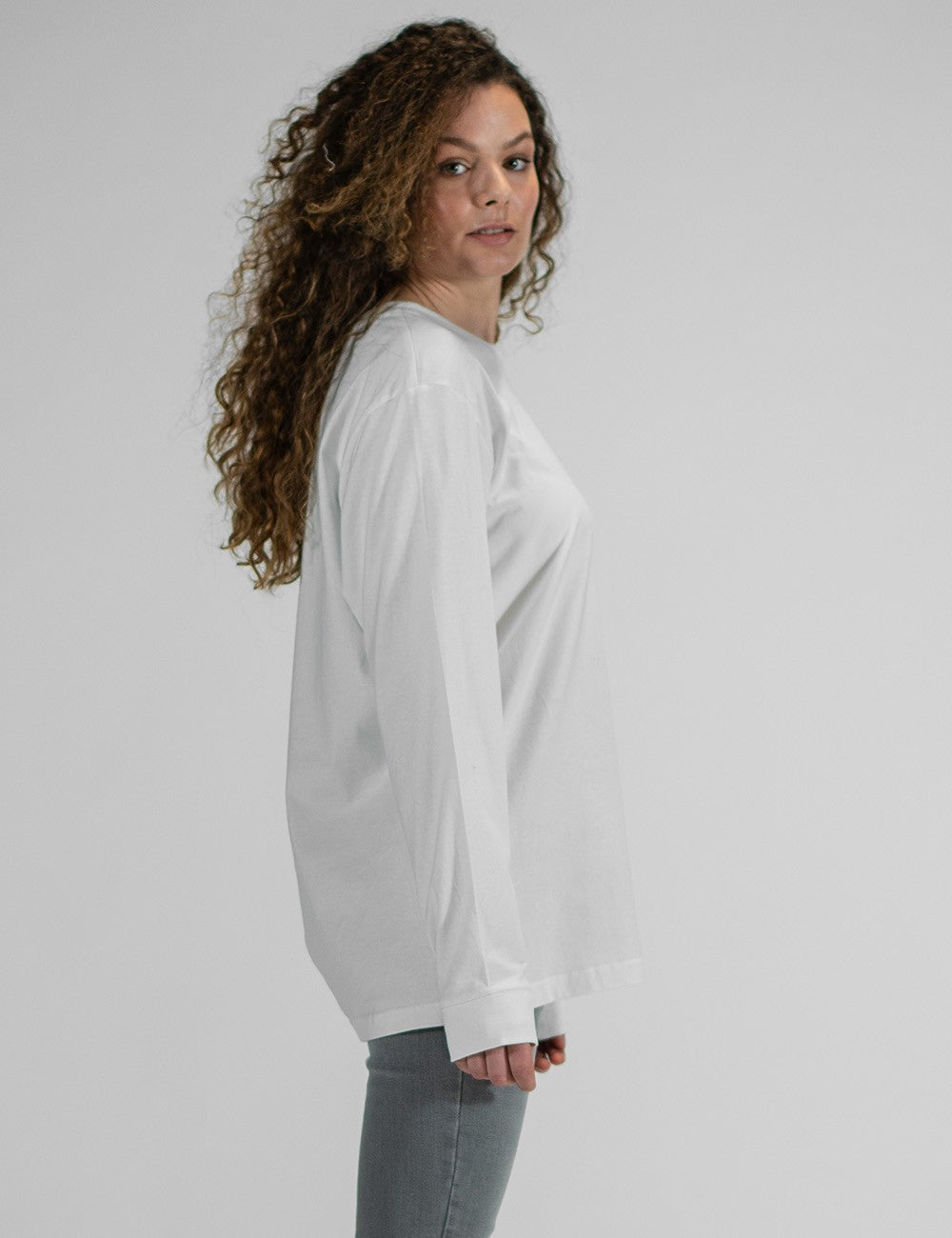 A female model wearing a plain white Longsleeve with Cuffrib from Rocket Science. t-shirt with a round neck and ribbed cuffs.