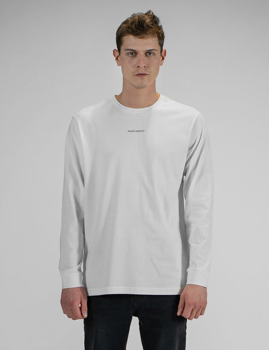 A young man wearing a white long-sleeve crewneck shirt with a small, minimalist "Rocket Science" logo printed in the center of the chest. He has paired the shirt with slim-fit black jeans.