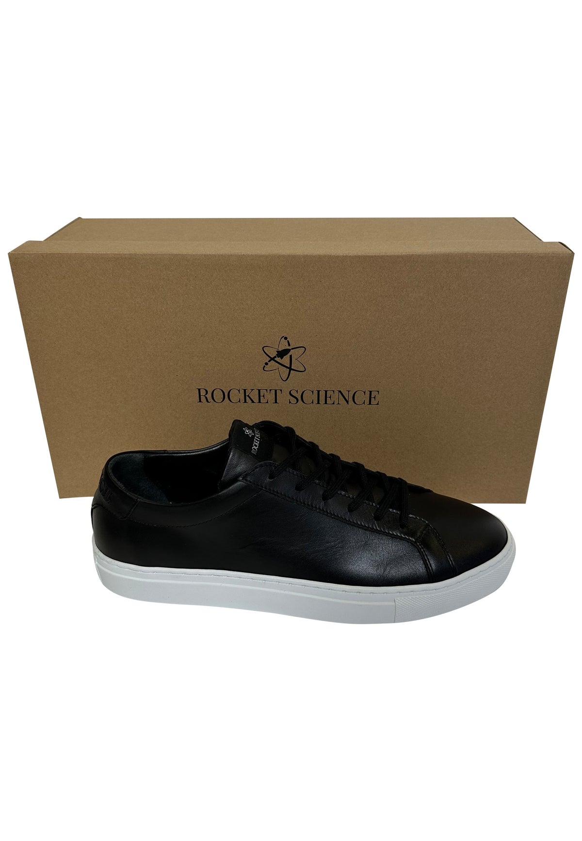 A black leather sneaker with a white sole sits in front of its cardboard shoe box, which features a logo of an atom and the words "ROCKET SCIENCE".