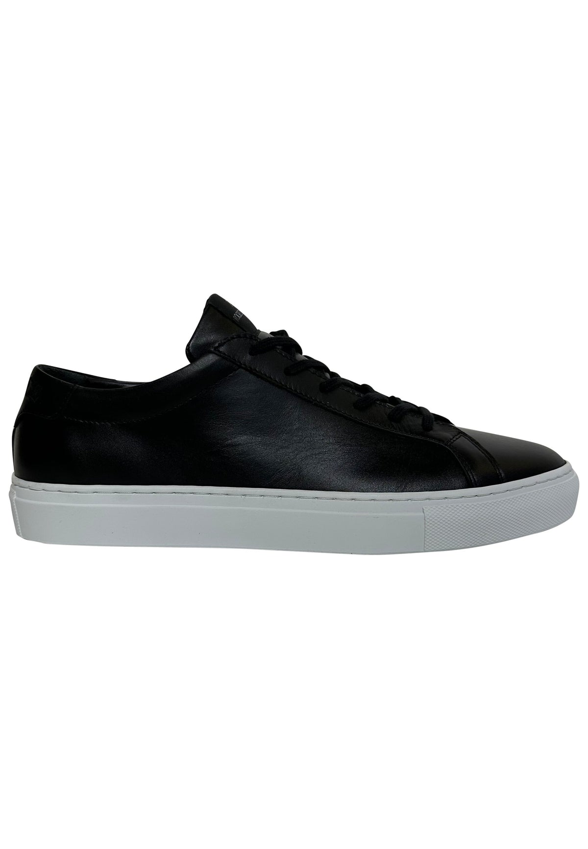 A side-profile view of a minimalist, low-top men's sneaker featuring a black leather upper, matching black laces, and a thick, contrasting white rubber sole.