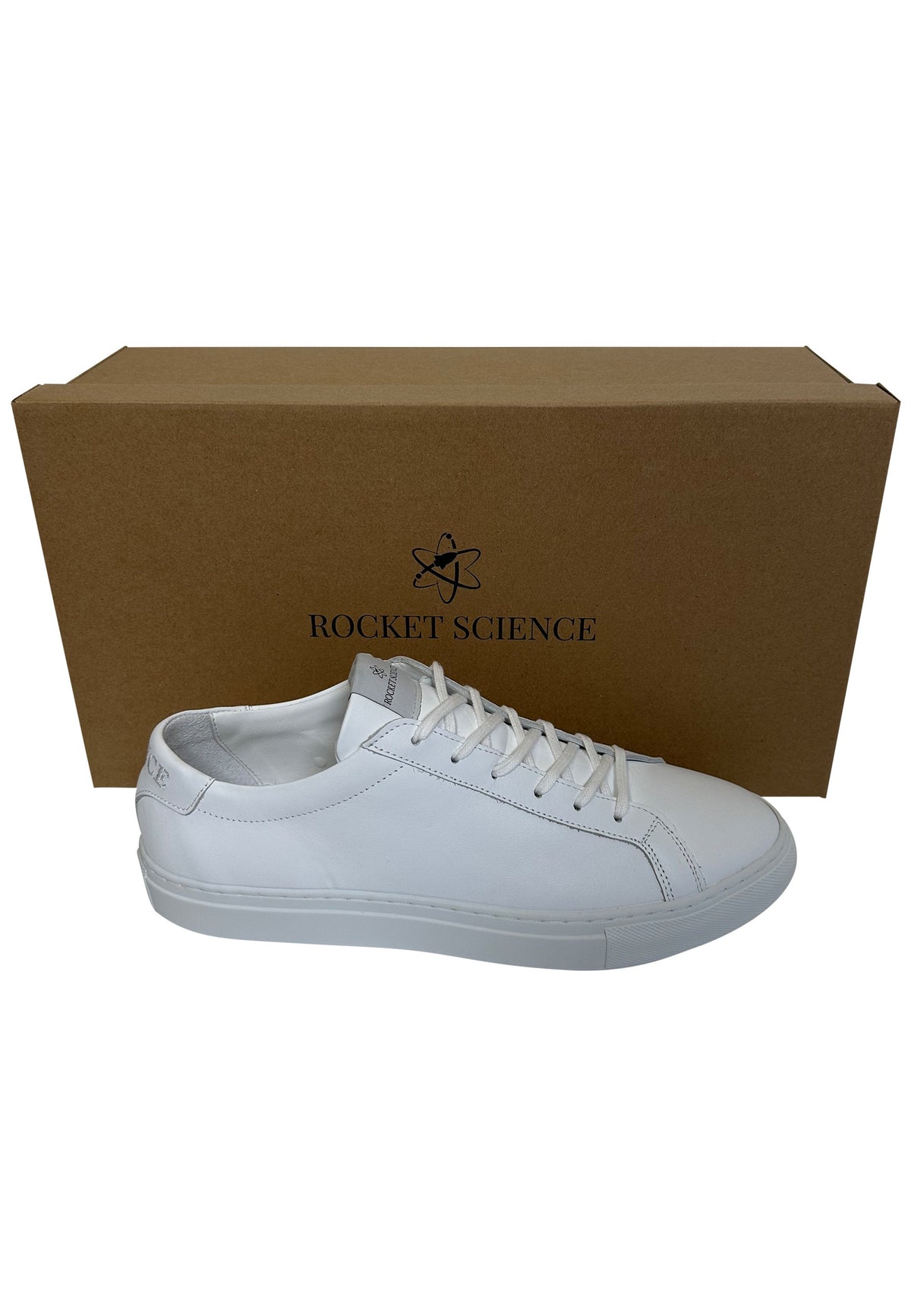 A white leather low-top sneaker shown in profile in front of its brown cardboard packaging box, which features the Rocket Science brand logo.
