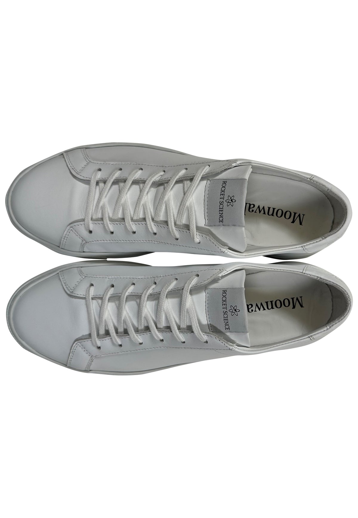 A top-down view of a pair of white minimalist low-top sneakers arranged horizontally next to each other against a plain white background.