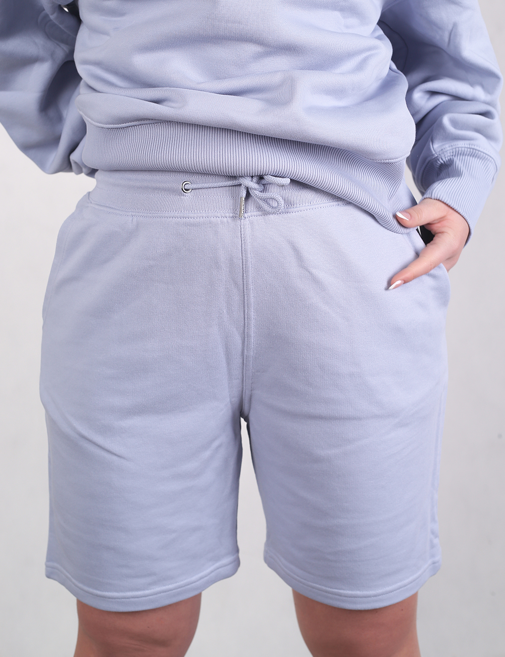 A close-up shot focusing on the high-waisted fleece sweatshorts which feature a ribbed elastic waistband with a drawstring and side pockets.