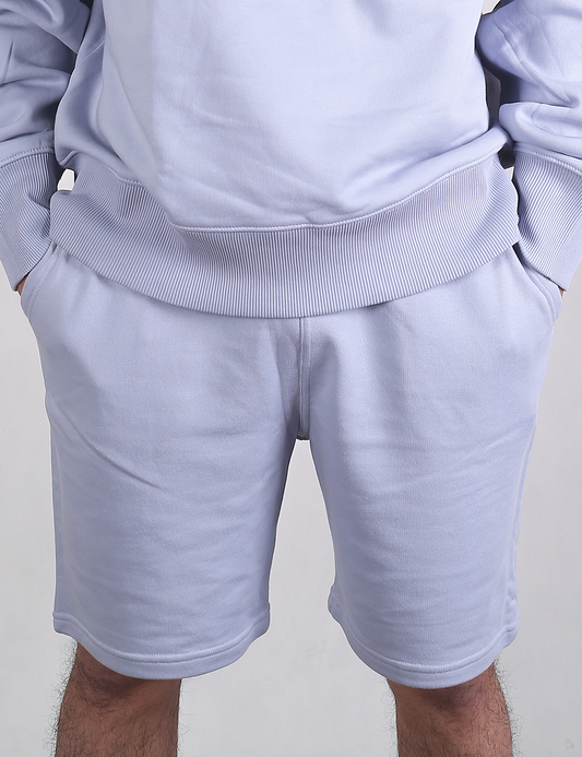 Close-up of a person wearing a matching light blue sweatshirt and sweatshorts lounge set.