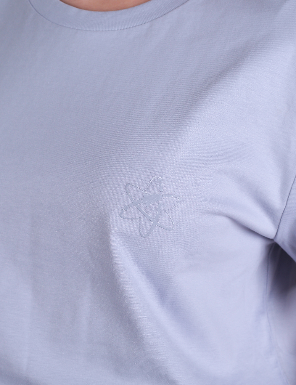 A close-up shot of a light lavender-colored t-shirt featuring a subtle, tone-on-tone Rocket Science logo outline printed or embroidered on the left chest area.