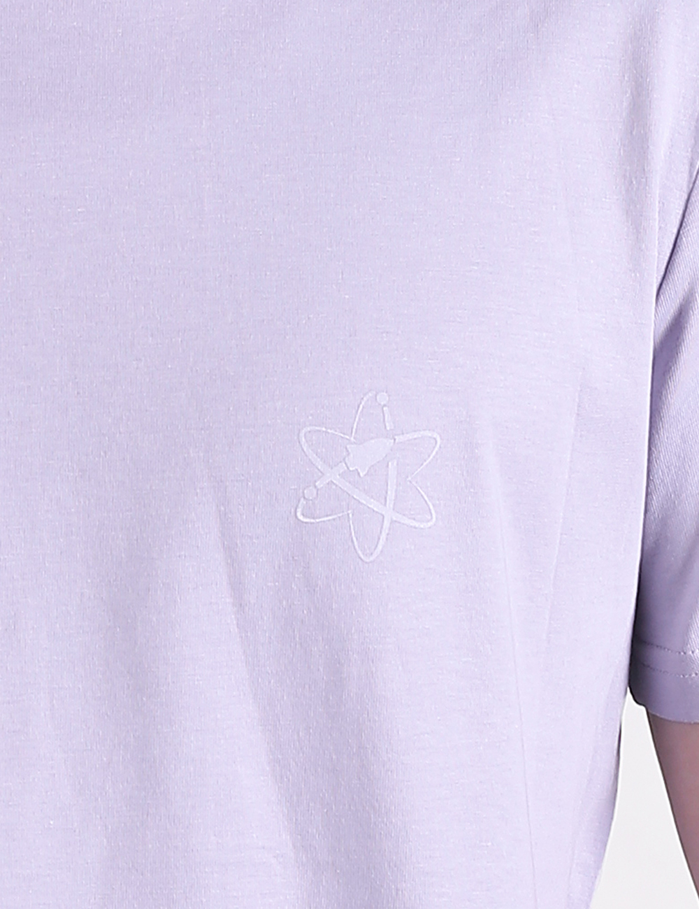 A close-up shot of a lavender-colored t-shirt featuring a small, white outline of an atom symbol printed on the left chest area.