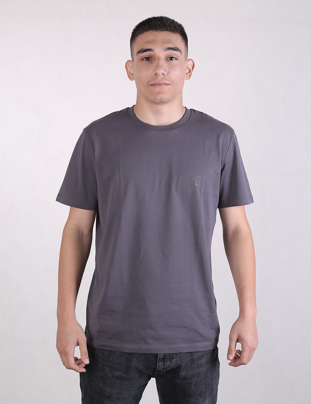 A front-facing shot of a man wearing a dark charcoal gray crewneck t-shirt and dark jeans against a plain white background.