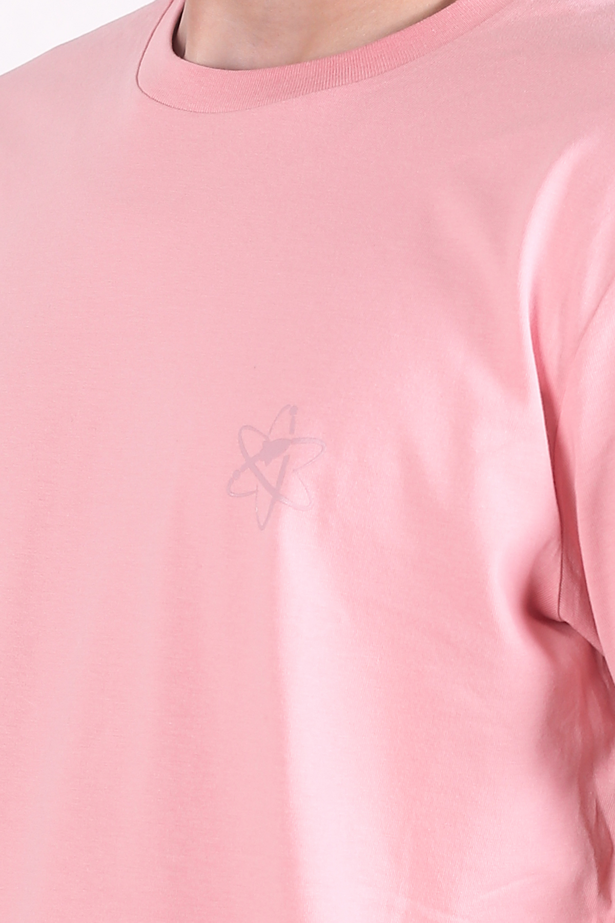 A close-up of a light pink crewneck t-shirt featuring a subtle, tonal Rocket Science logo on the left chest, worn by a model.