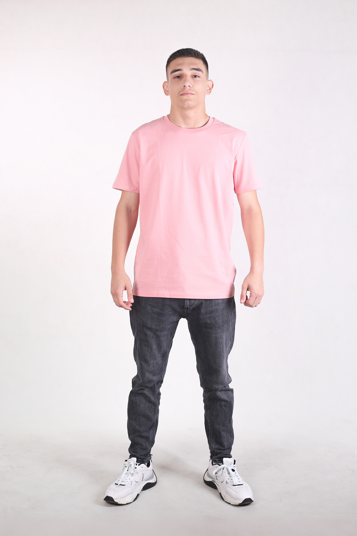 Person wearing a pink t-shirt and dark jeans on a white background