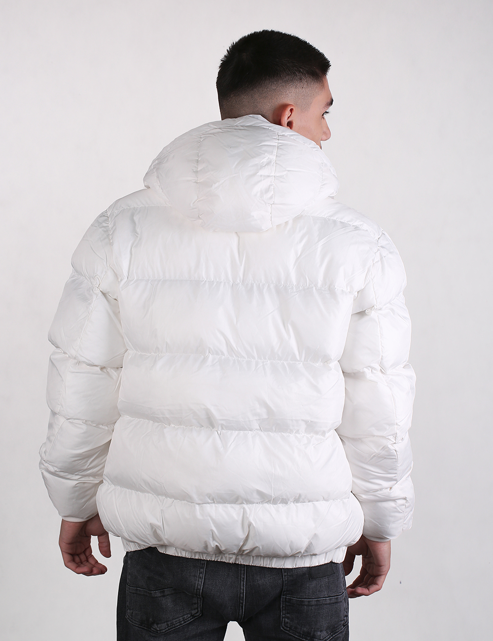 Person wearing a white puffer jacket on a plain background