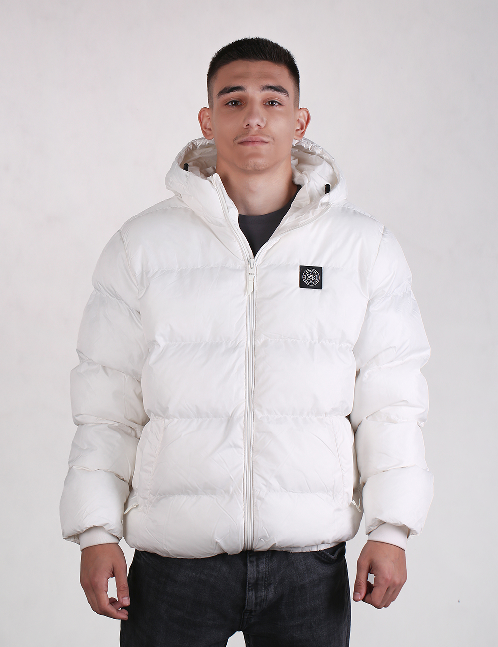 Person wearing a white puffer jacket with a brand logo on a plain background