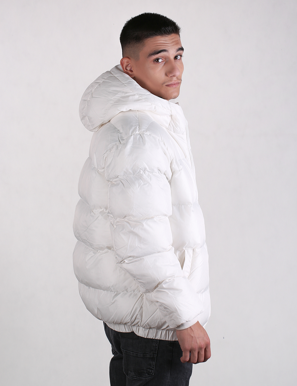 Man wearing a white puffer jacket against a plain background