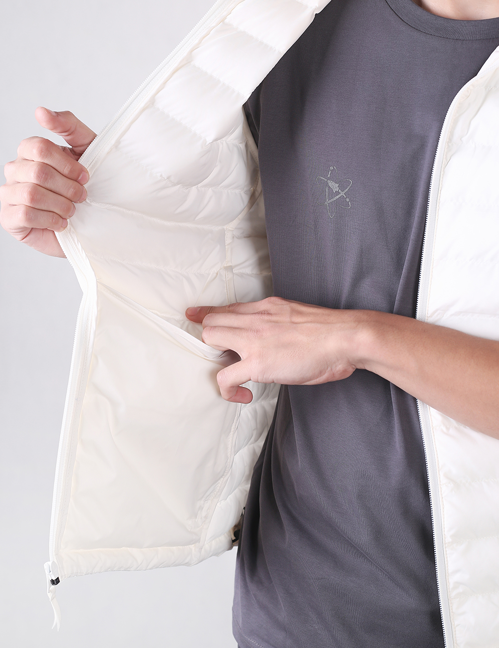 A close-up of a person wearing a white puffer jacket over a dark gray t-shirt, showing the interior lining and pocket of the jacket.