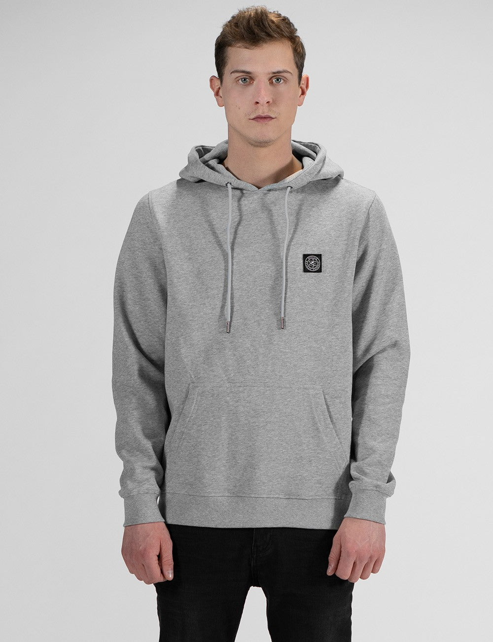 A man with brown hair is modeling a light heather grey hoodie.