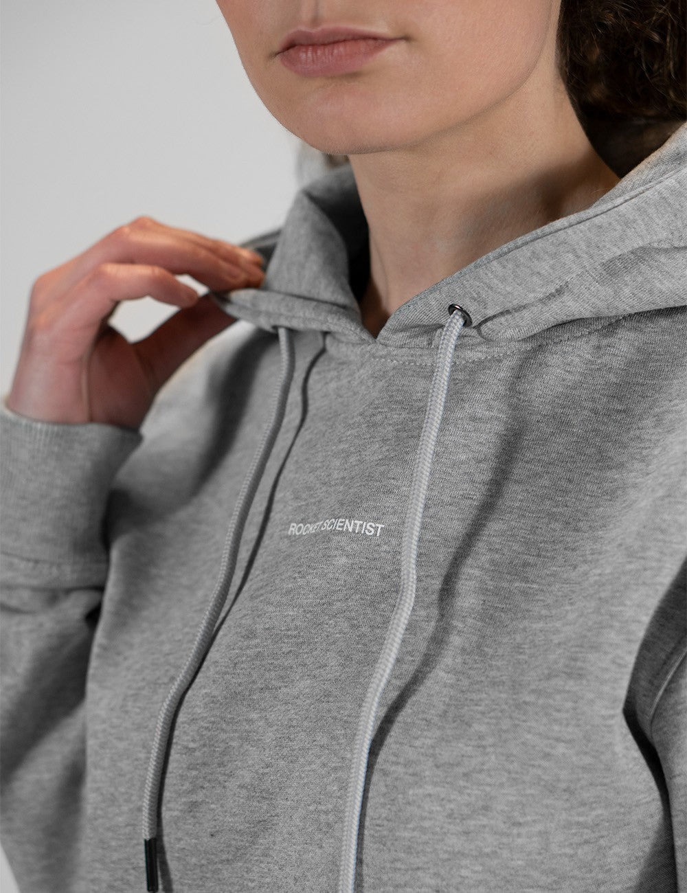 The image shows a person wearing a grey heather cotton hoodie with a small white chest Rocket Scientist logo