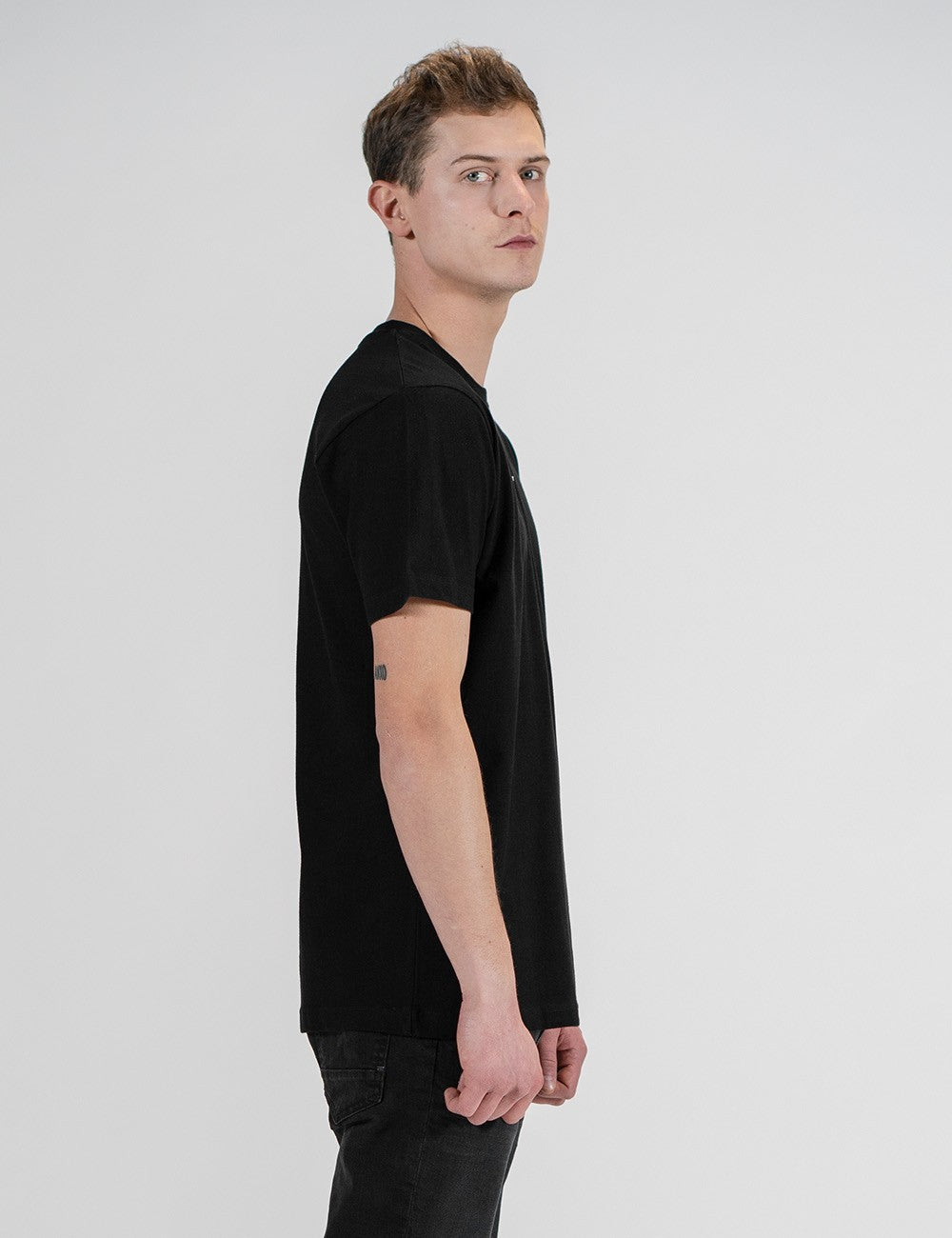 Man showcasing a black round-neck T-shirt with the words “Rocket Scientist” on the front.