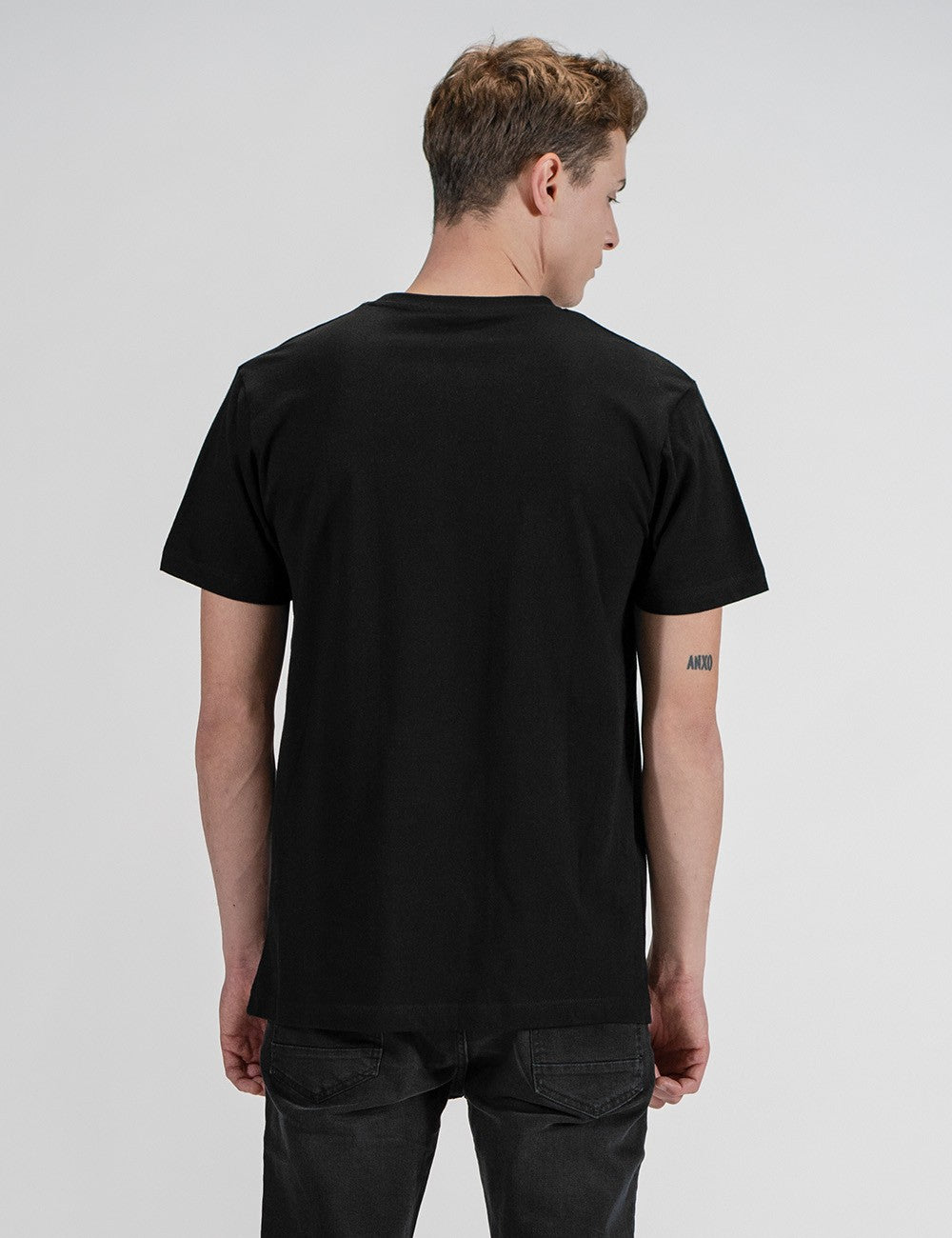 Man showcasing a black round-neck T-shirt from the back.