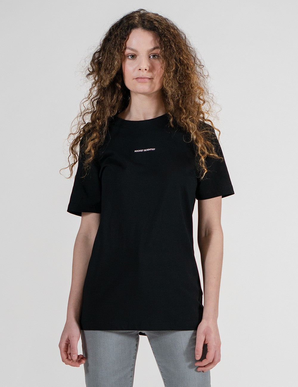 Woman showcasing a black round-neck T-shirt with the words “Rocket Scientist” on the front.