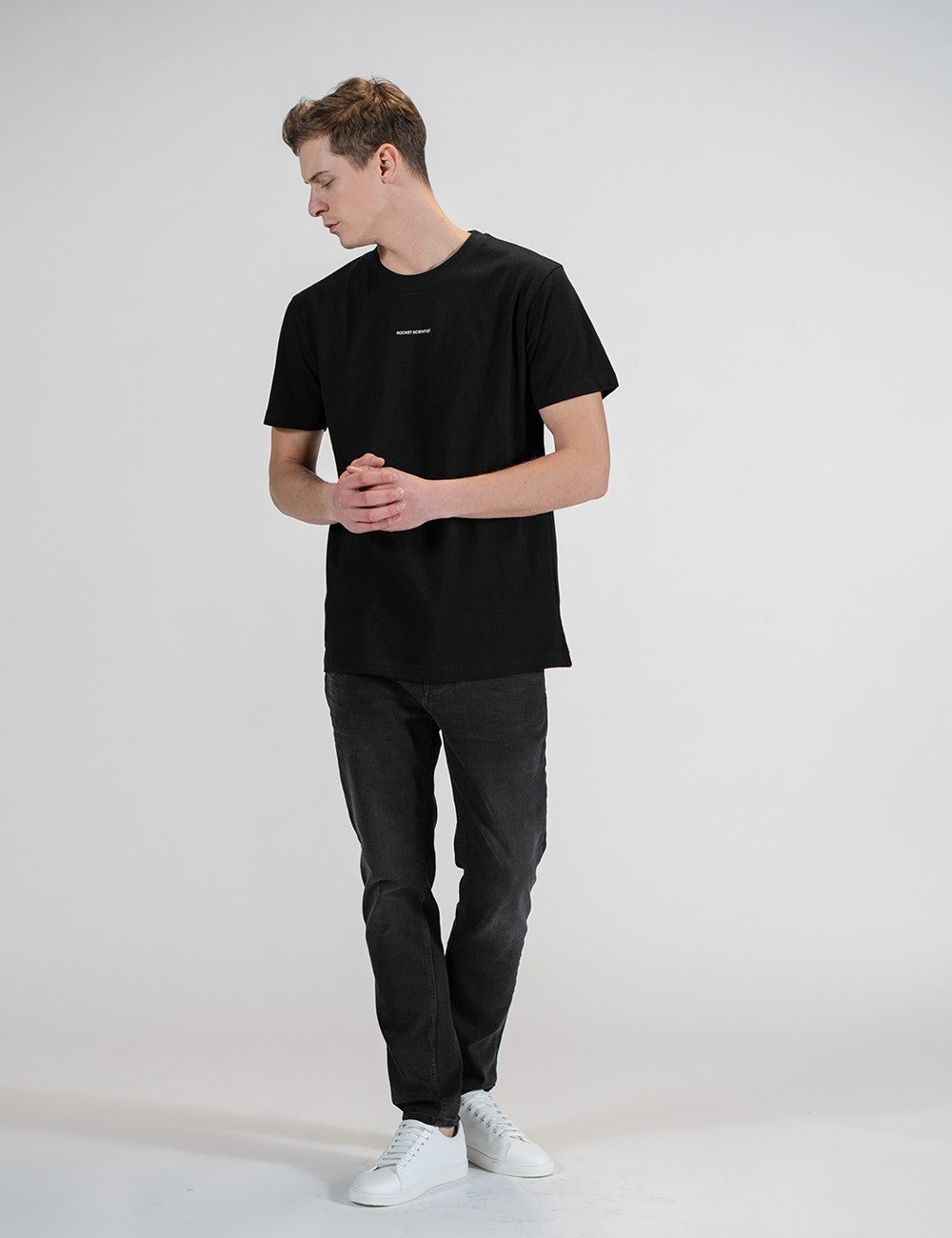 Man showcasing a black round-neck T-shirt with the words “Rocket Scientist” on the front.