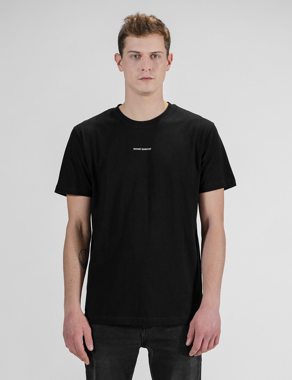 Man showcasing a black round-neck T-shirt with the words “Rocket Scientist” on the front.