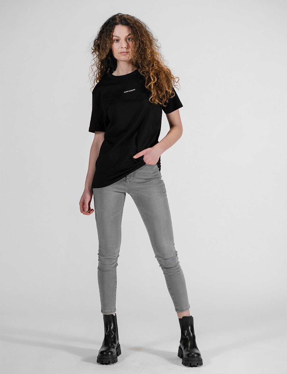 Woman showcasing a black round-neck T-shirt with the words “Rocket Scientist” on the front.