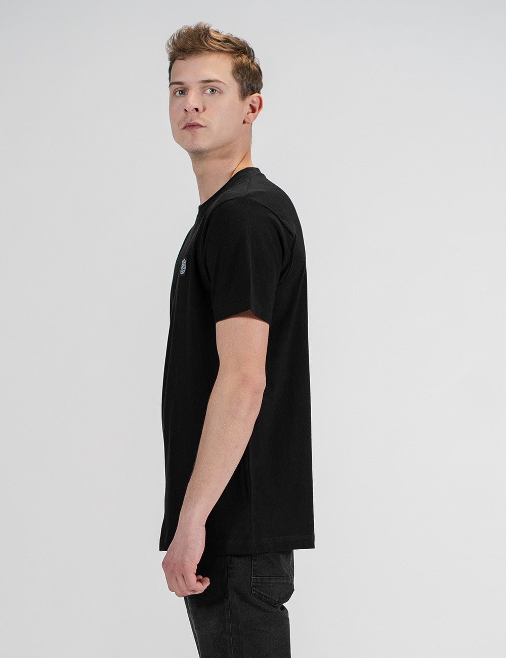 This image shows a side pose of young man wearing a black cotton crew-neck t-shirt 