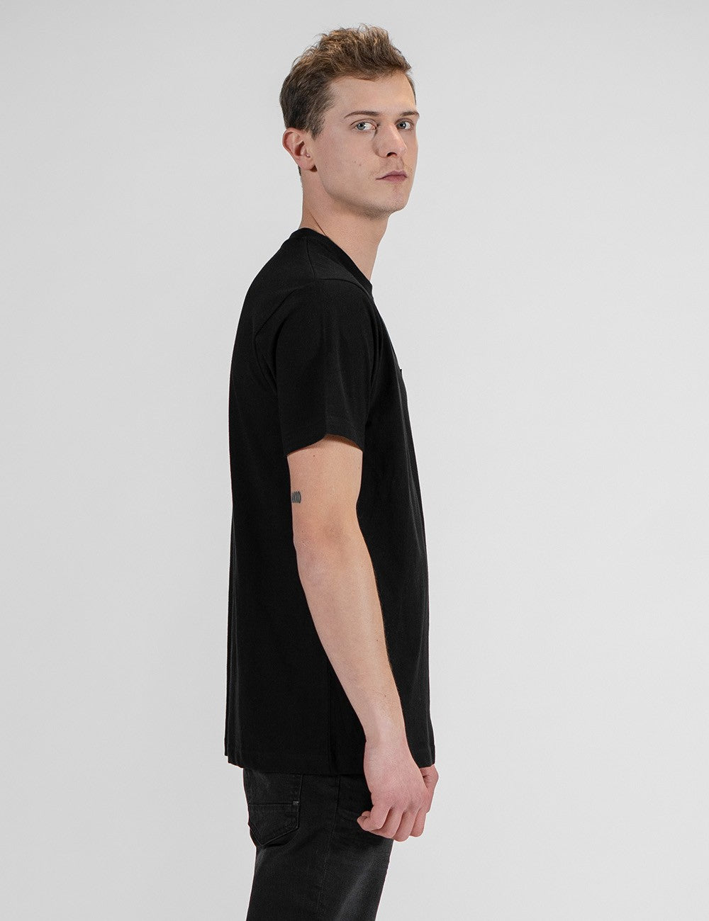 This image shows a side pose of young man wearing a black cotton crew-neck t-shirt 