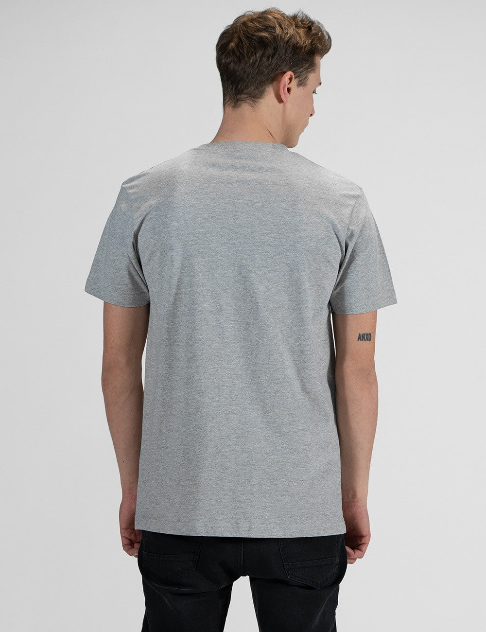 This image shows the rear pose of a young man with light brown hair, wearing a light grey Rocket Science short-sleeve t-shirt .