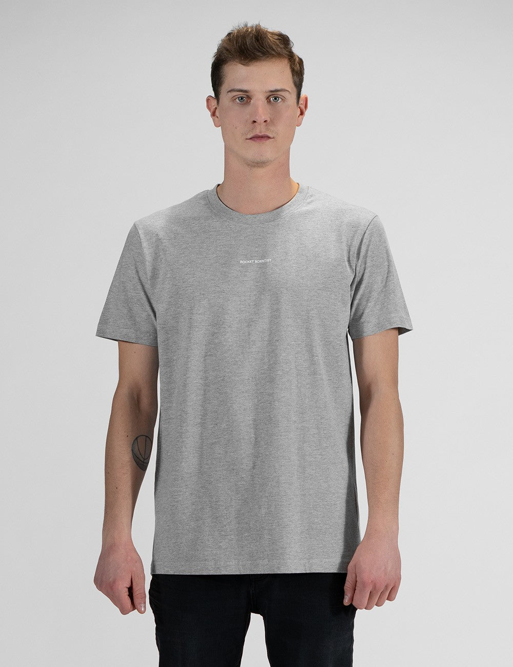 This image shows front pose of a man wearing a casual grey crew-neck t-shirt with a front print "Rocket Scientist", and dark denim jeans.