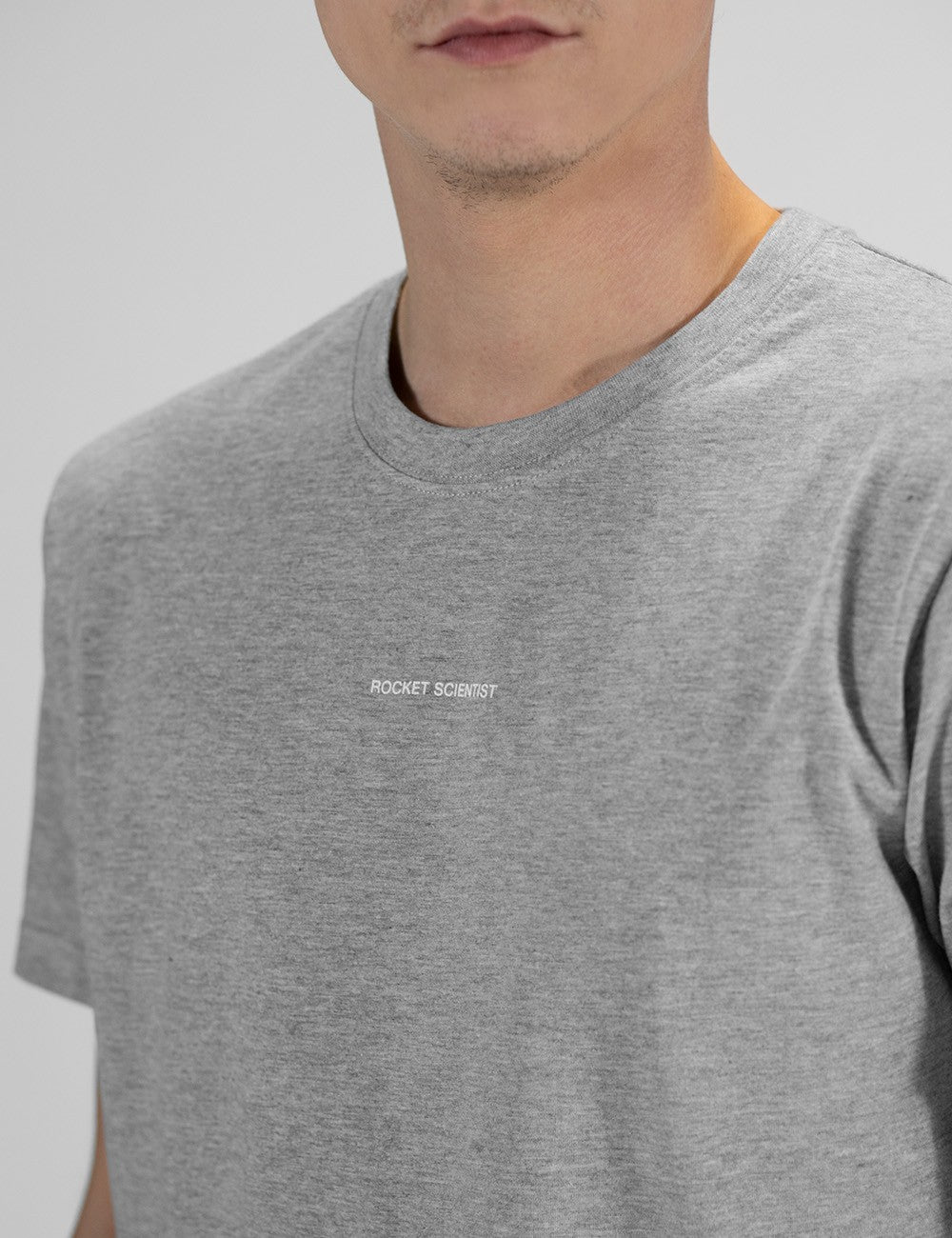 The image shows a heather grey crewneck t-shirt with a small "Rocket Science" chest print.