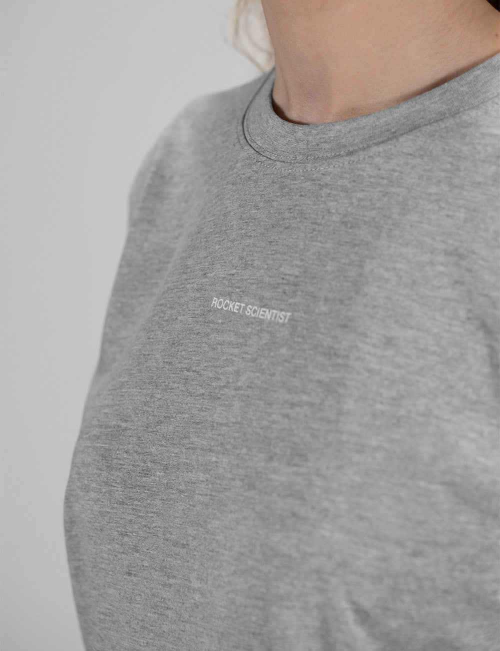 The image shows a grey crewneck sweatshirt  featuring small white "ROCKET SCIENTIST" text branding on the chest.